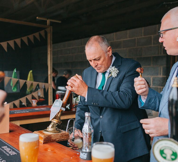 Guests look on as Father of the Bride is pouring his own beer behind the self serve bar.
