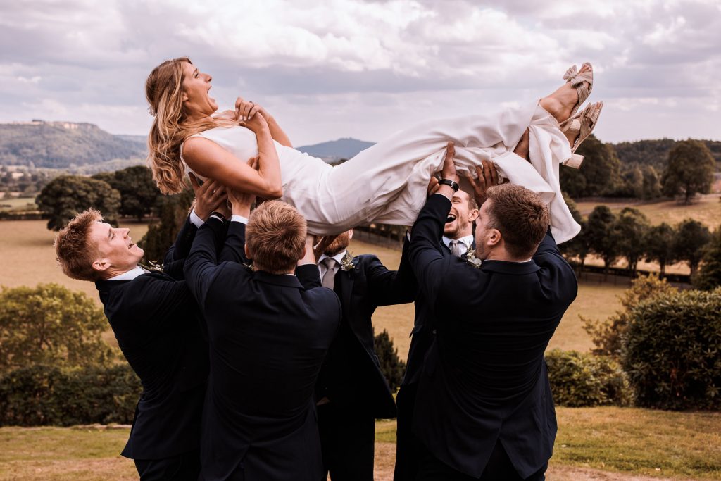 Sarah is thrown up into the air by her groom and groomsmen.