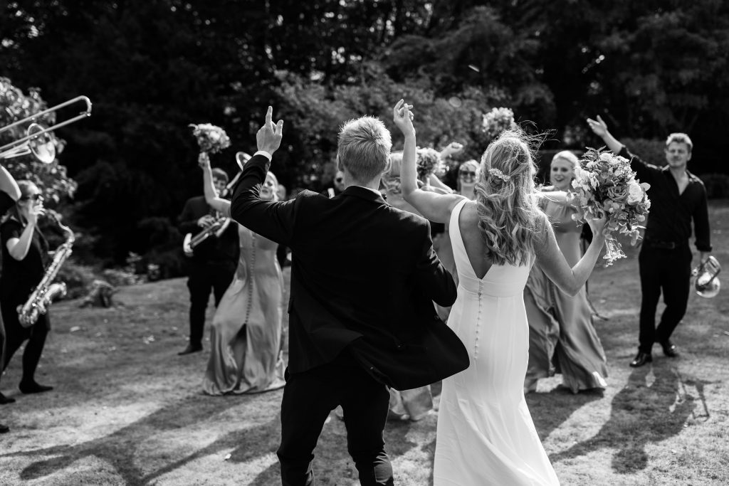 Black and white image. Guests sing and dance to the brass band.