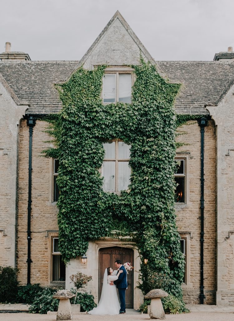 Bride and groom embrace in front of the Georgian House at Hyde House in the Cotswolds.