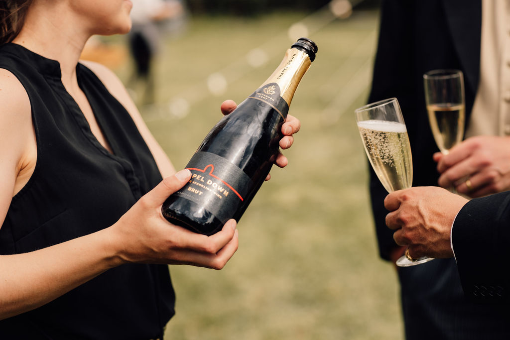 The wedding planner can be seen serving champagne to guests during the marquee drinks reception.